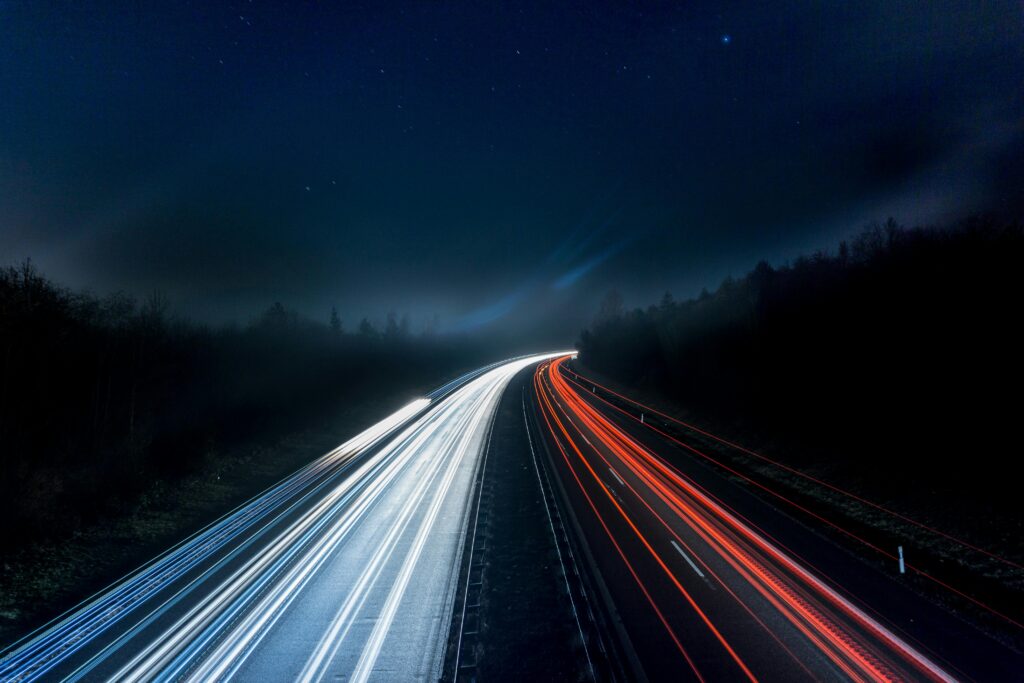 Co to jest Speed i dlaczego ma znaczenie w marketingu internetowym? Long exposure night shot capturing stunning red and white light trails on a highway under a starry sky.